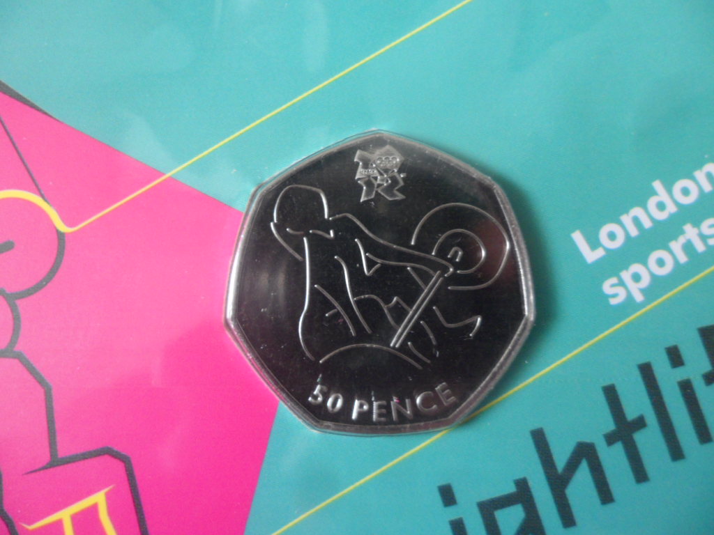 เหรียญที่ระลึก การแข่งขันกีฬาโอลิมปิก - โอลิมปิก ลอนดอน 2012; THE ROYAL MINT ชนิด 50 เพนซ์ ลายยกน้ำหนัก ใหม่ / OLYMPICS International Sports Tournament Souvenir Coin - OLYMPICS LONDON 2012; THE ROYAL MINT 50 Pence WEIGHTLIFTING NEW