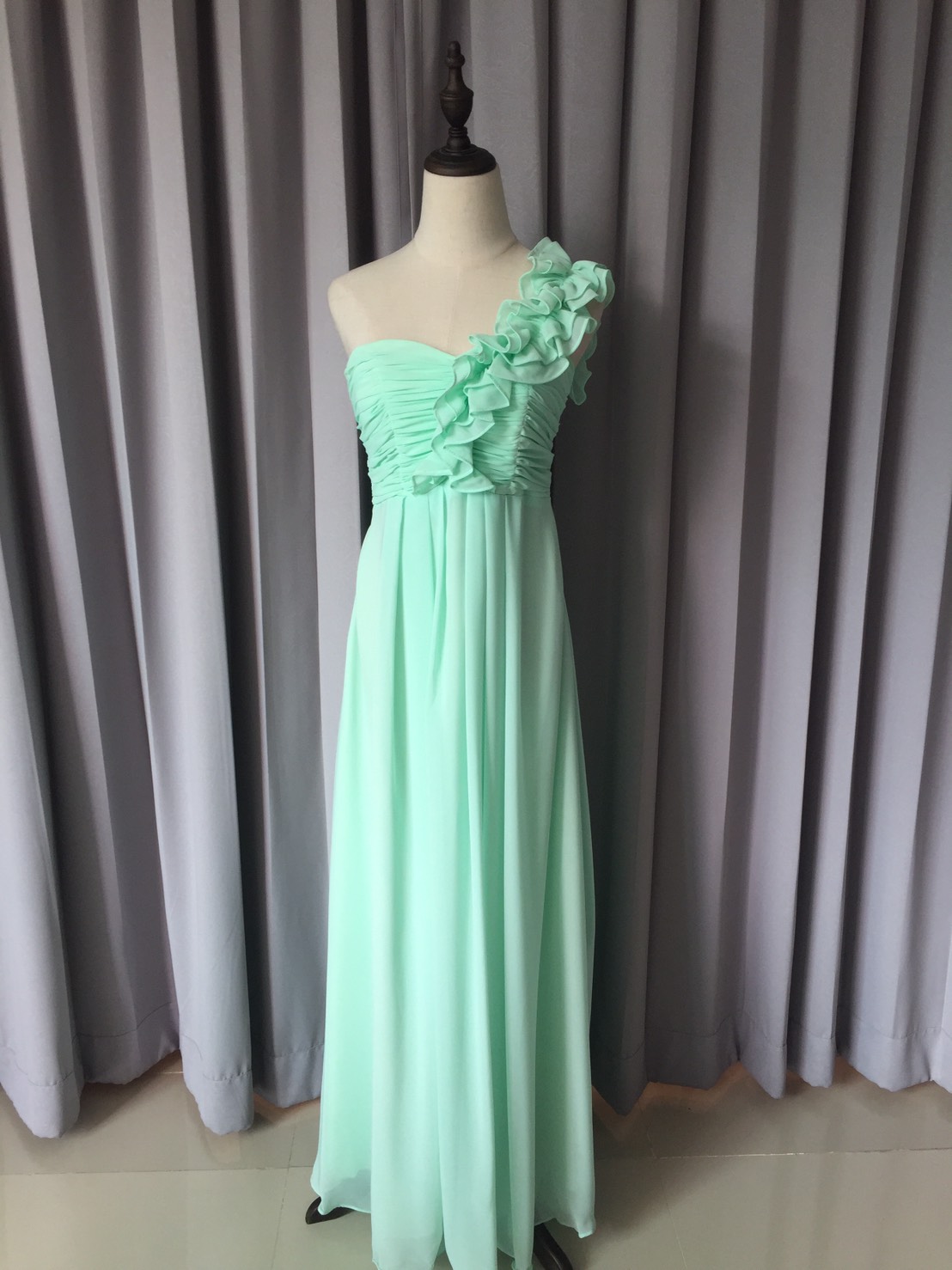 พร้อมเช่า ชุดราตรียาว ไหล่เดียว จับเดรปหน้าอก แต่งระบายช่วงไหล่ สีเขียวอ่อน