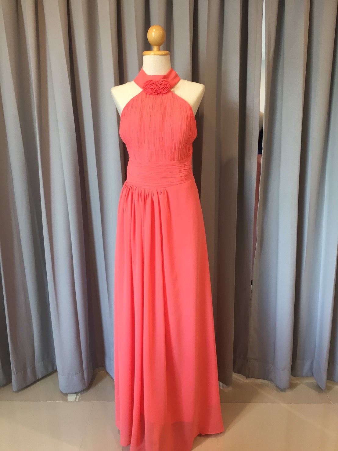 พร้อมเช่า ชุดราตรียาว สีโอรส คล้องคอ อกอัดพลีทตลอดจนถึงช่วงเอว เพิ่มดอกใต้คอ